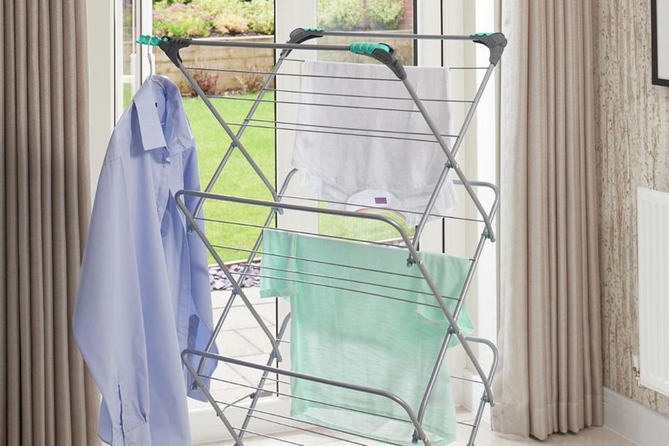 A 3 tiered clothes airer placed by a French window. 