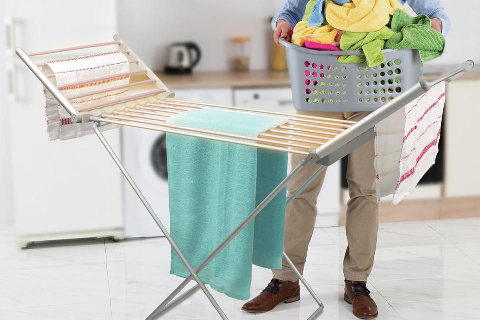 A man draping clothes on a heated clothes airer.