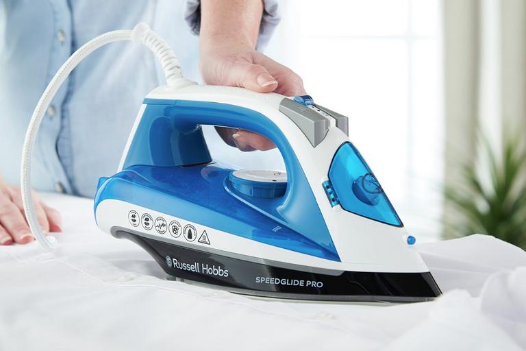 Close up of a woman ironing a white shirt with a blue and white steam iron.