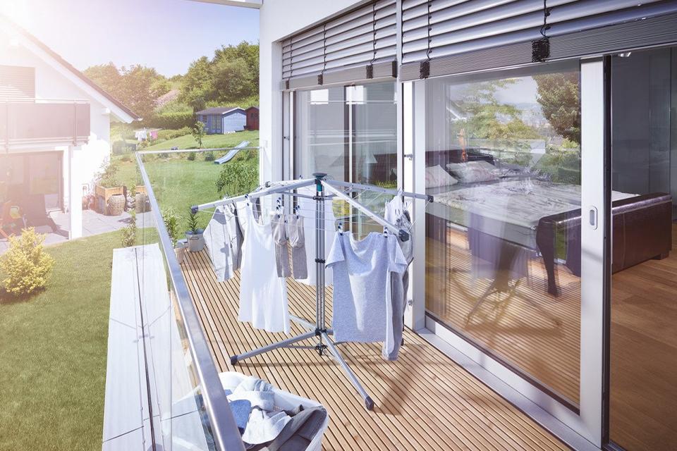 Clothes drying on a wheeled rotary airer placed in a balcony.