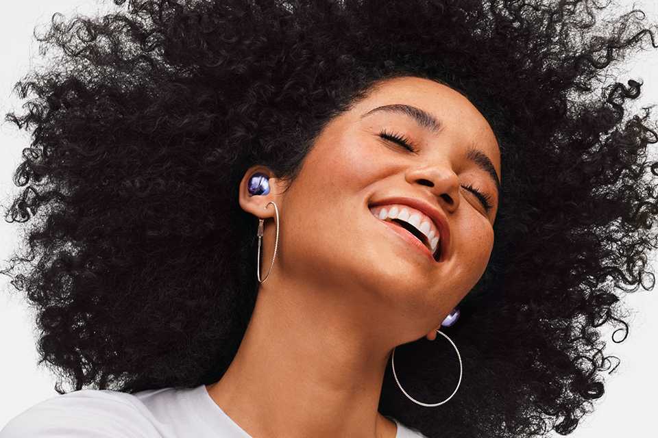 A woman smiling while enjoying music on her Samsung Galaxy Buds Pro.