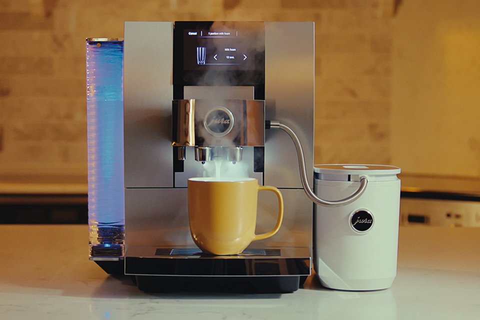 A Quiet Mark certified bean to cup coffee machine frothing milk into a yellow mug on the counter.