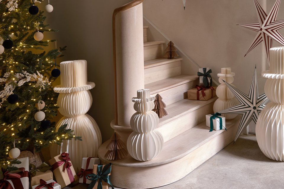 Image of a set of stairs surrounded by paper Christmas decorations with a white colour scheme