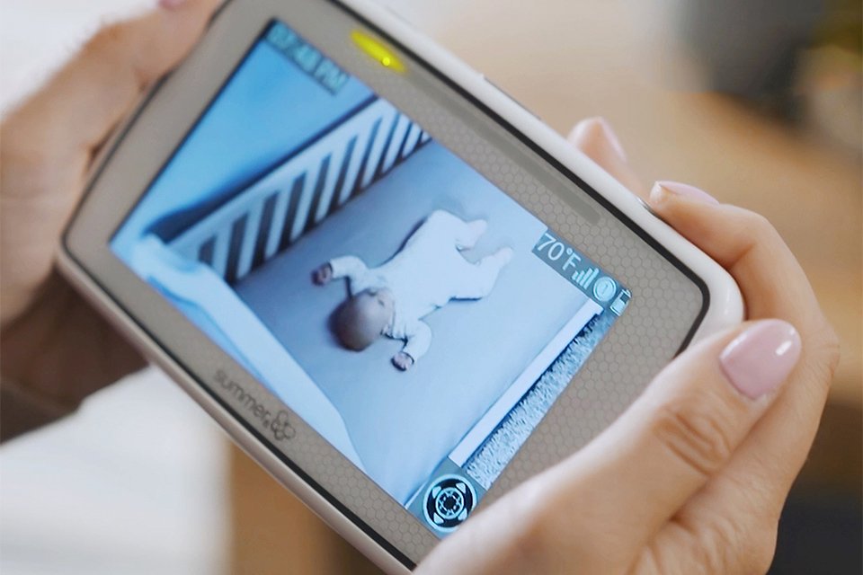 A parent watching a baby on the baby monitor screen from their living room.