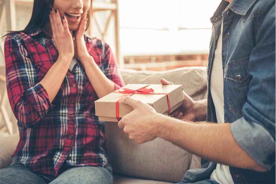 woman excited to be receiving a gift from a man.