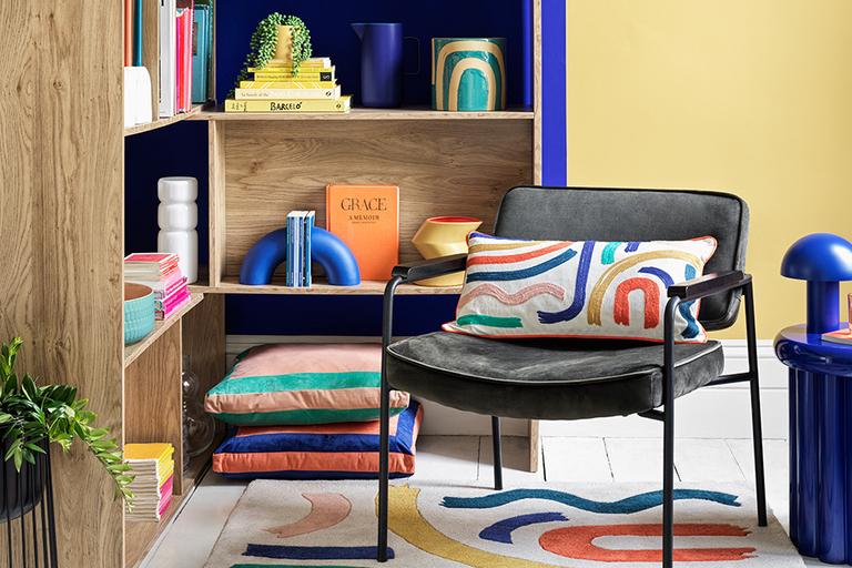 Colourful living room with armchair, rug, storage unit and side table.