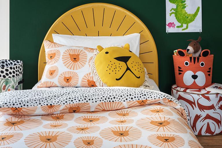 Kids bedroom with a yellow fabric style bed, with white pattened bedding and dark green kids bedroom furniture.