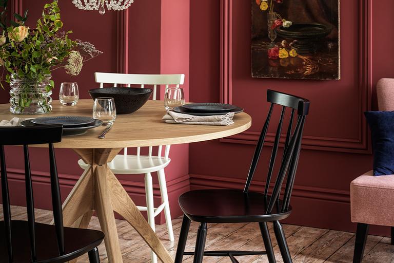 Maroon coloured dining room with black and white tables around an oak table.