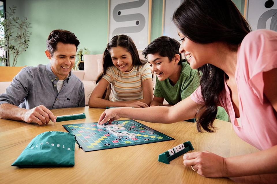 A family of four gathered around a table to play Scrabble.