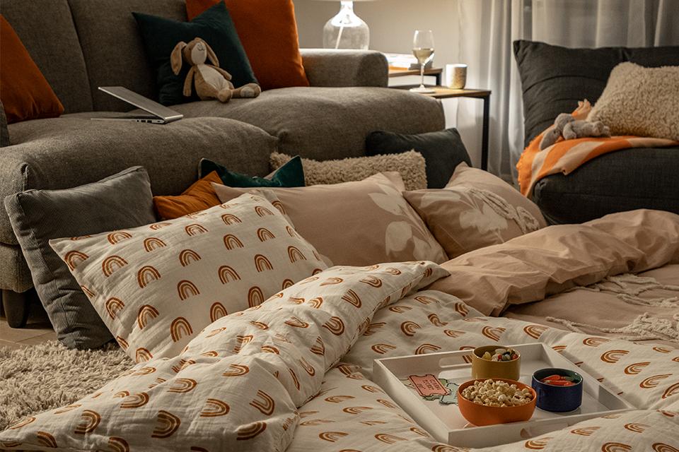Image of a living room with lots of pillows and duvets for movie night.