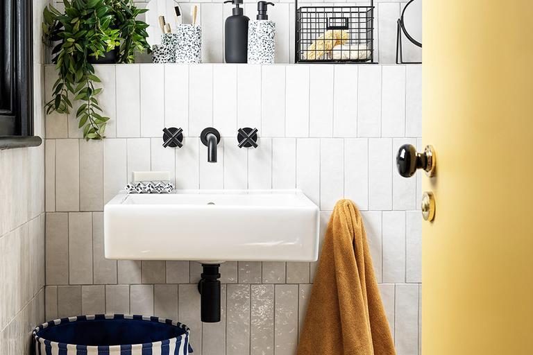 Bathroom with mustard towel and white and navy laundry basket.
