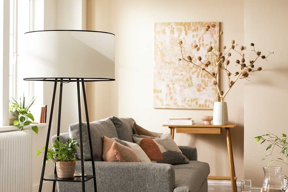 A Habitat shelved floor lamp in black and white next to a grey sofa. 