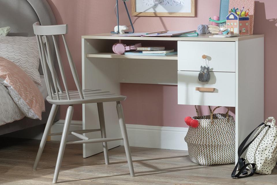 Image of a small white desk with a grey chair in a pink room.