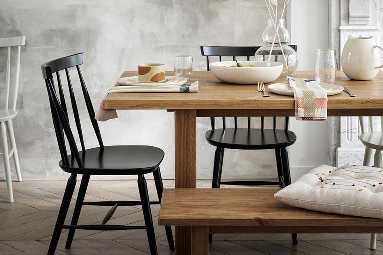 Rustic style dining table with black dining chairs and wooden benches.