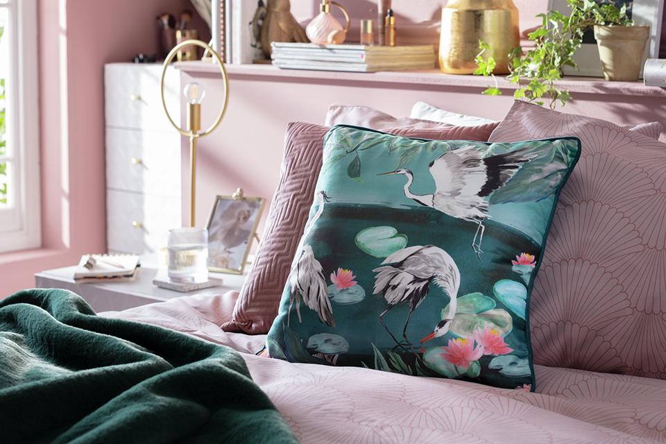 A Habitat Japonica crane patterned teal cushion and throw in a metal storage.