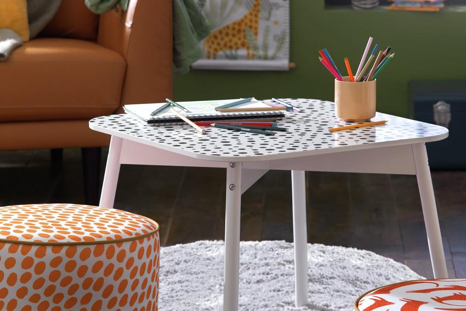 Craft table with pencils and paper on a round grey rug.