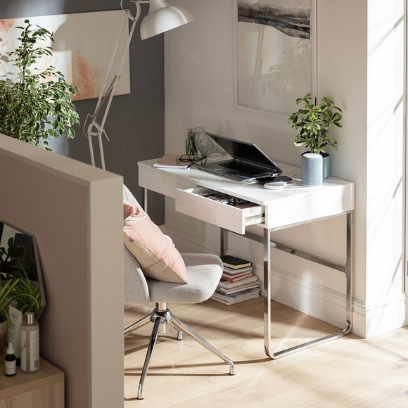 An image of a small white desk with a chair and adjustable floor lamp.
