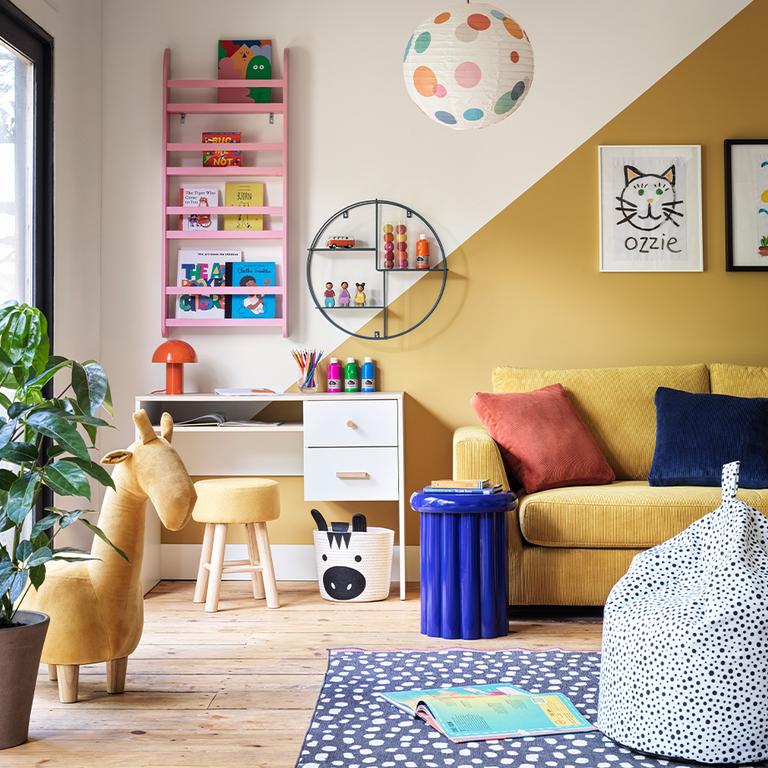 Colourful playroom with giraffe stool and white desk.
