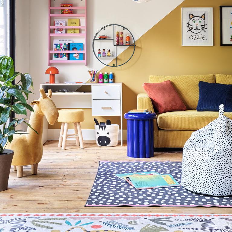 Colourful playroom with giraffe stool and white desk.
