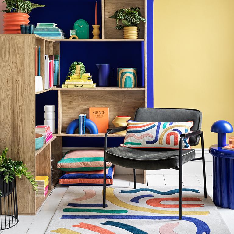 Colourful living room with bookcase, armchair and patterned mat.