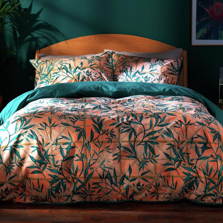 Image of a bed in a green room with pink and teal floral bedding.
