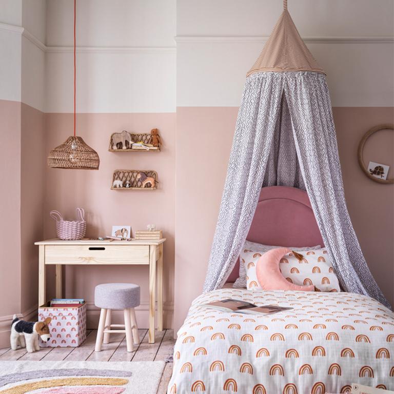 Image of a blush pink and white kids' bedroom with a canopy above the bed.