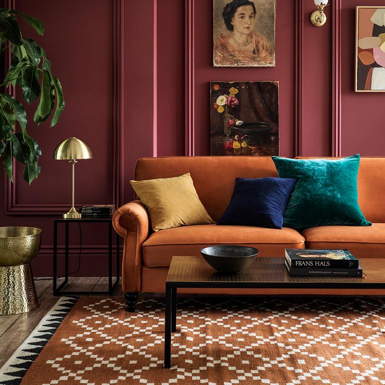 Image of deep purple living room with brunt orange, velvet sofa.