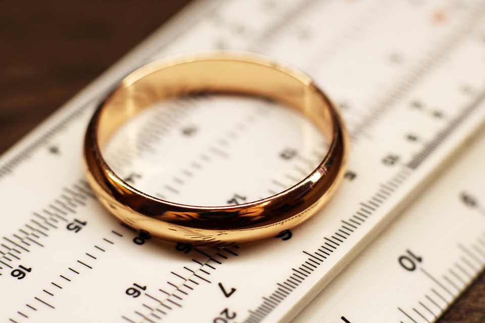 A gold wedding band placed on ring measuring scale. 