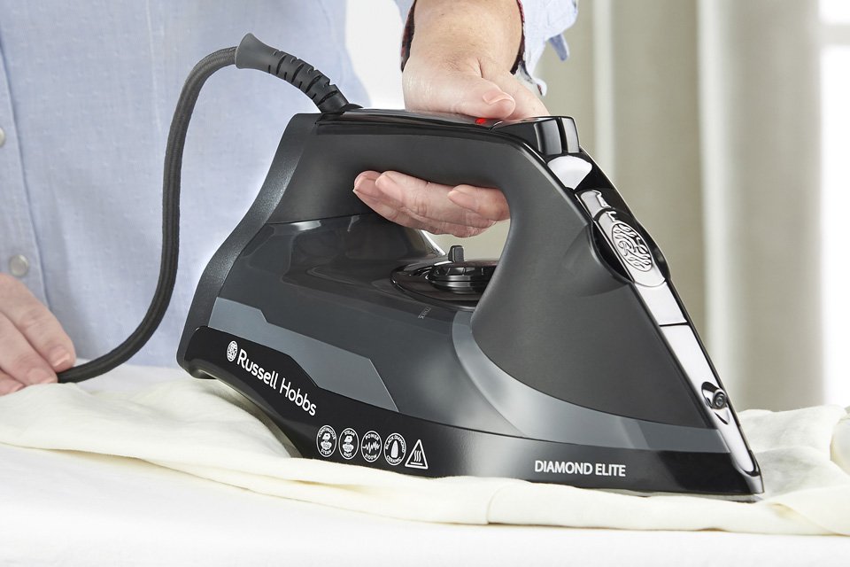 A Russell Hobbs black traditional steam iron in use.