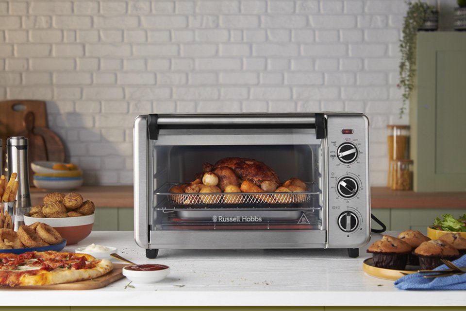 A Russell Hobbs mini oven sitting on a grey countertop with other food items.