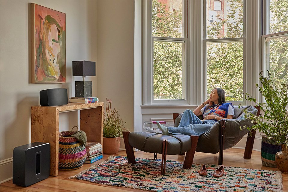A Sonos Sub 4 subwoofer set placed on a table in a living room.
