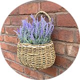 Wicker garden flower pot hanging on brick wall with lavender flowers inside.