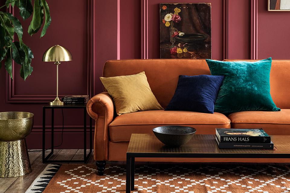 Image of an orange velvet sofa in a deep fuschia living room.
