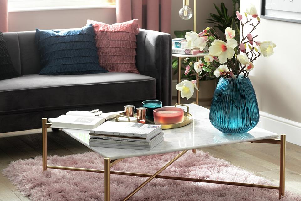 Image of a marble and brass coffee table in a white and pink living room.