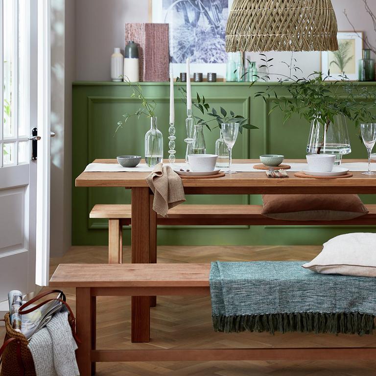 Image of a dining table and bench in a green room.