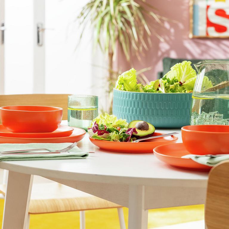 Image of a dining table with an orange dinner set.