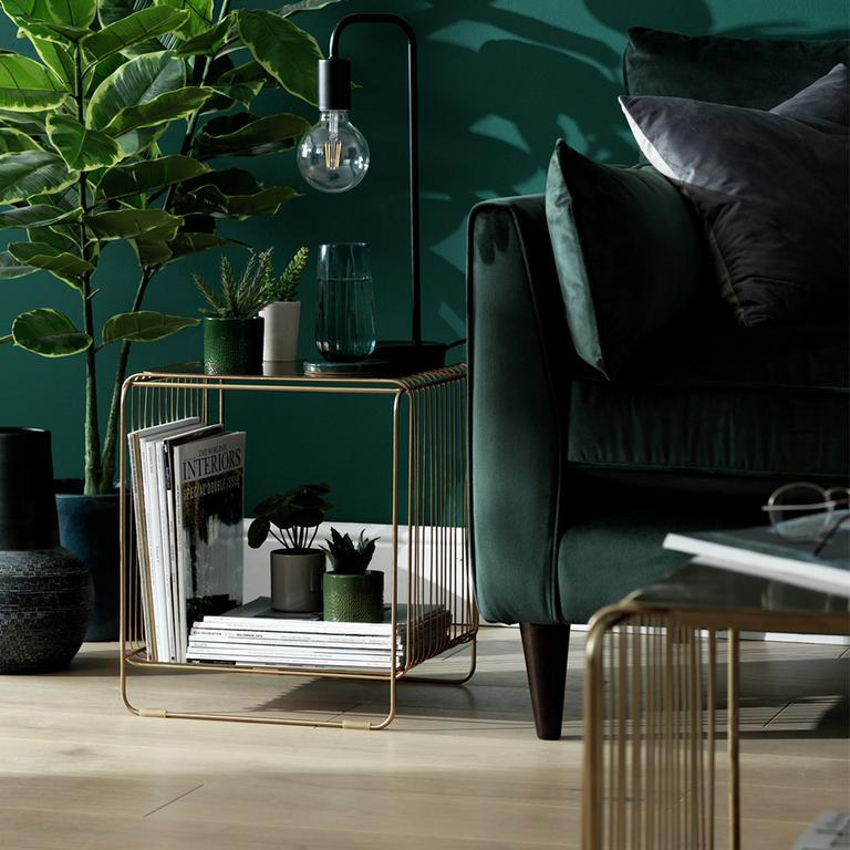 Image of a brass, wired side table in a green living room.