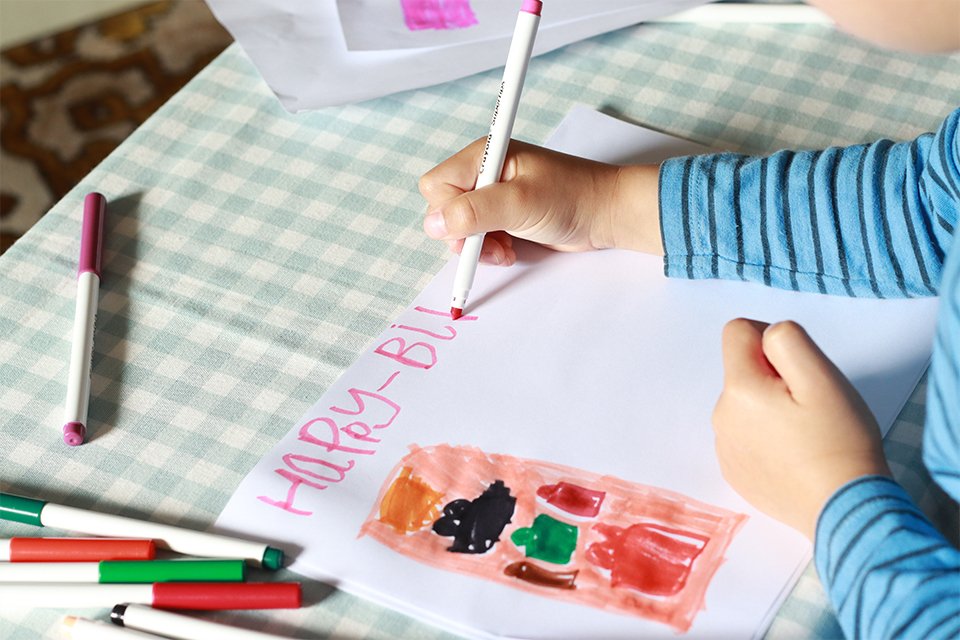 A kid painting a happy birthday card.