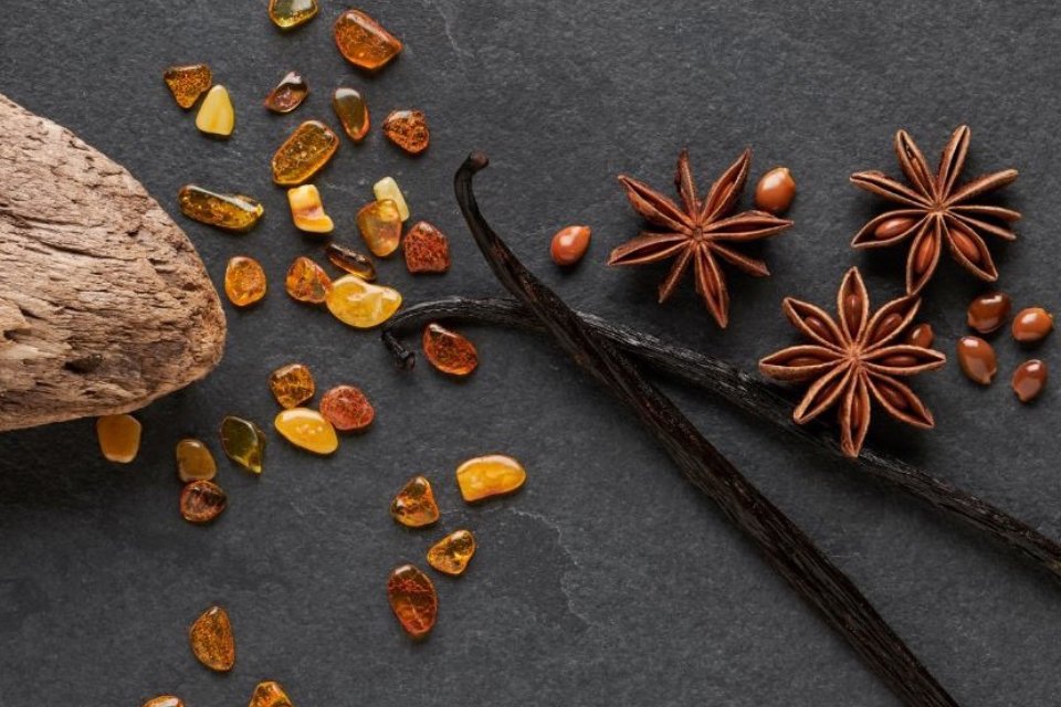 A flat lay of different spices and vanilla sticks against a black background.