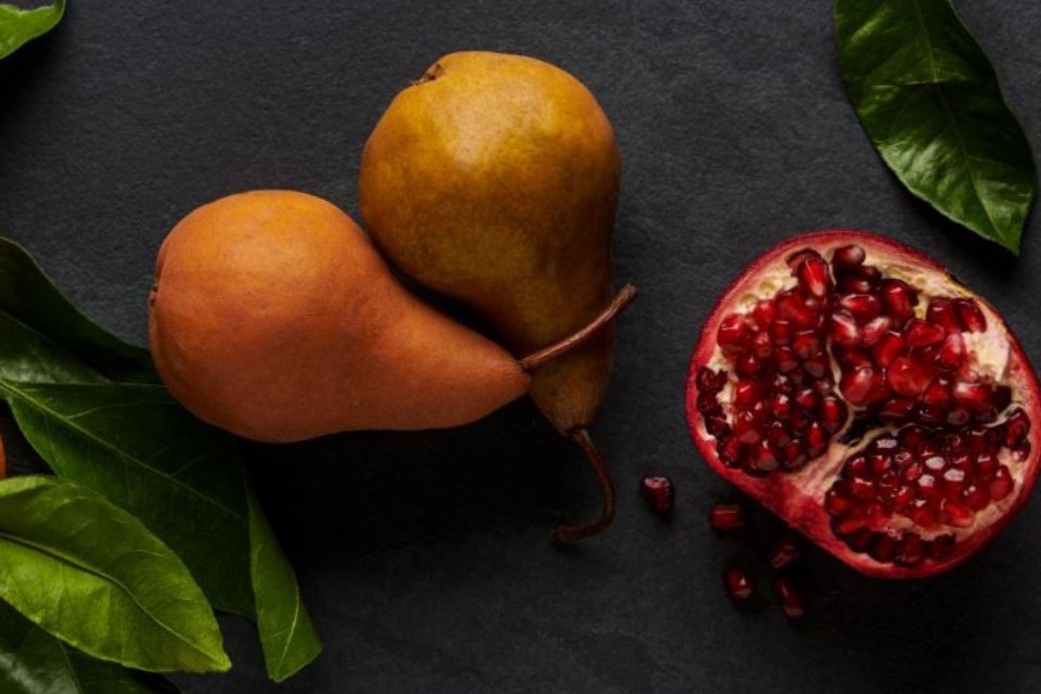 Two pears and a half pomegranate placed together.