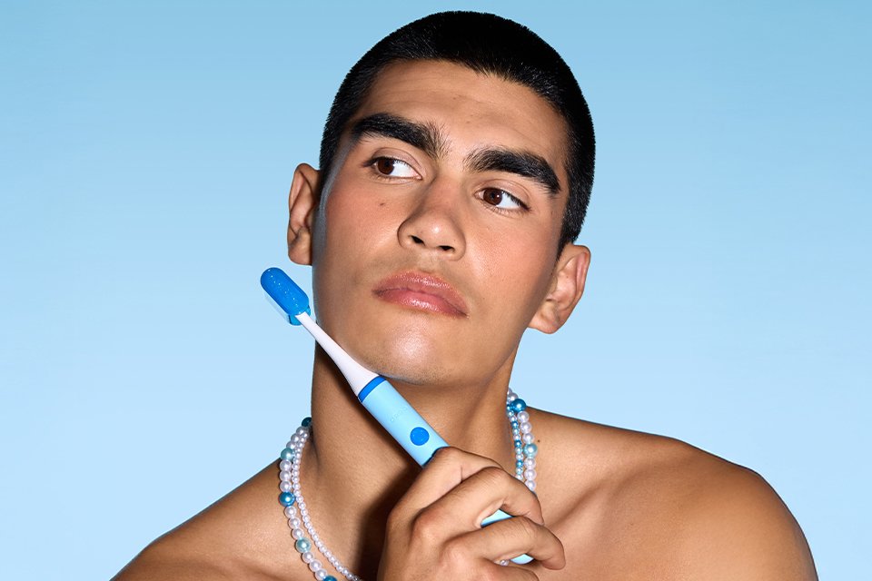  A man holding a blue Ordo Sonic Edge toothbrush.