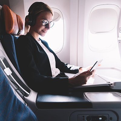 A woman using an iPad on an airplane.