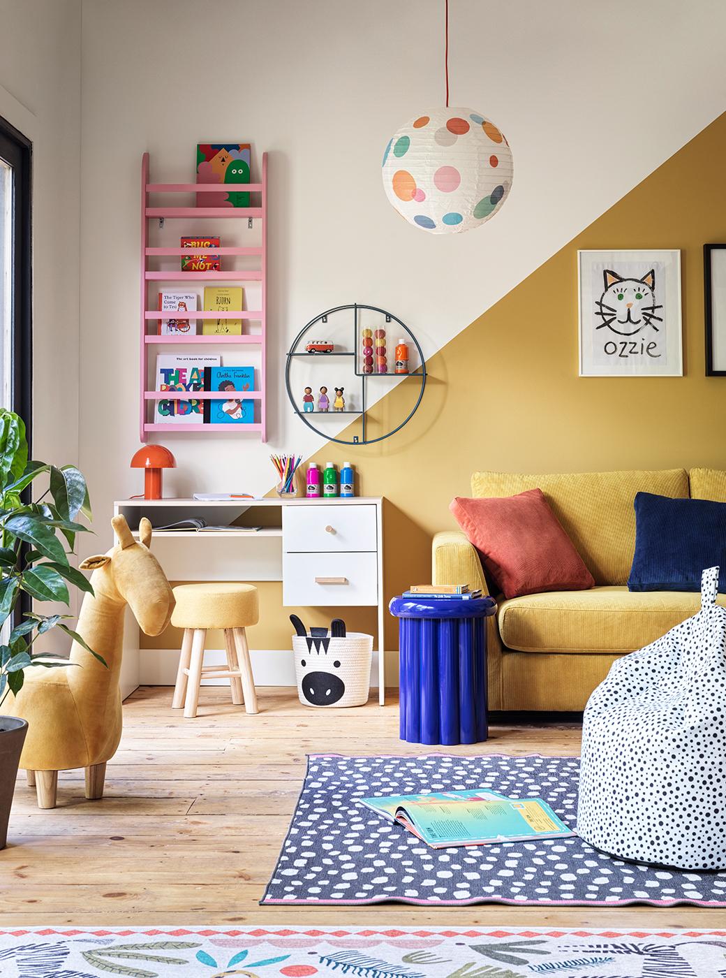 Kids playroom featuring a yellow sofa against a yellow wall with kids desk and chair and mounted bookcase.