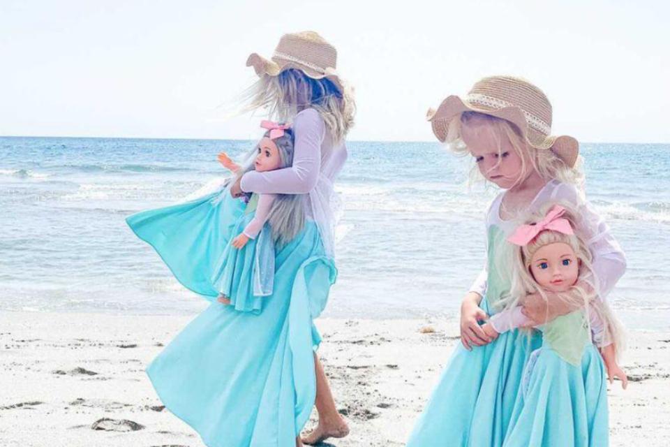 Two little girls on a beach, each with a DesignaFriend doll.
