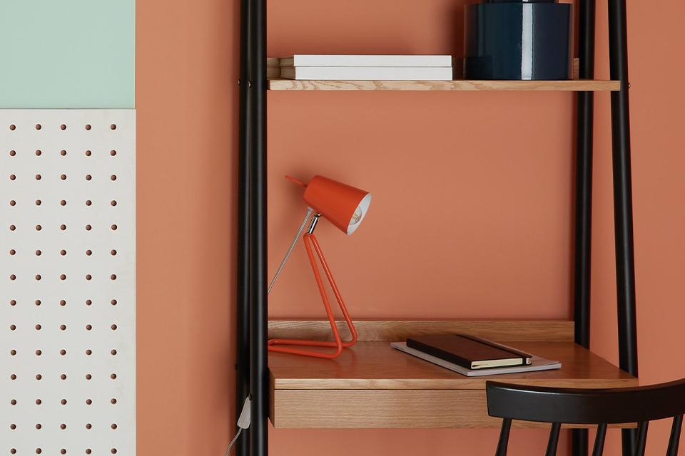 Image of a black ladder desk with an orange desk lamp.