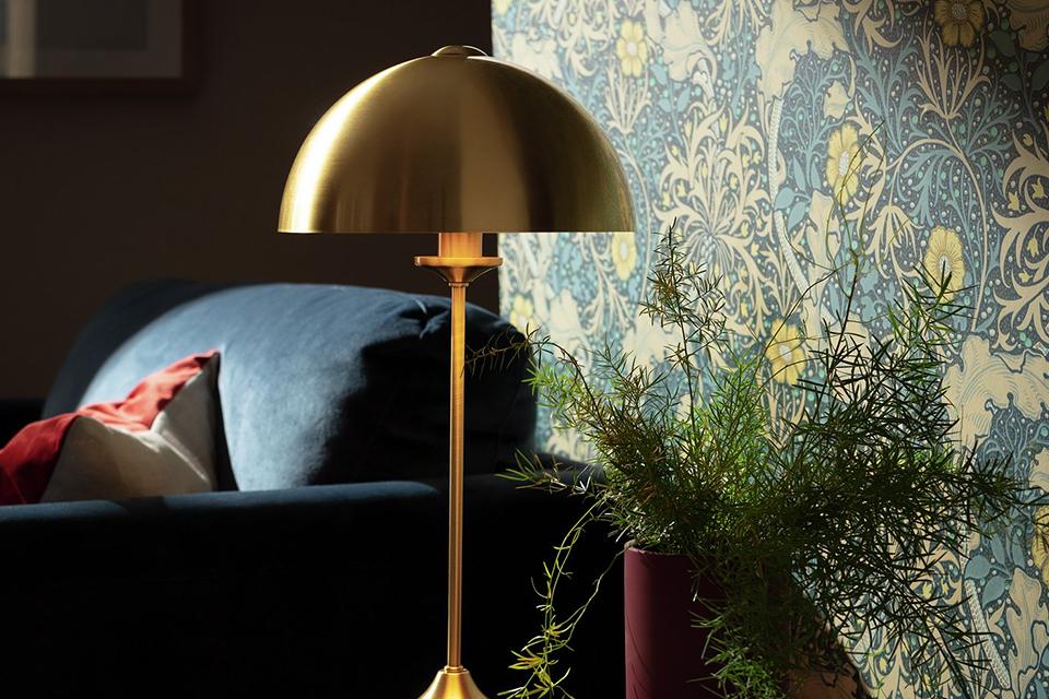 Brass lamp on side table next to navy sofa.