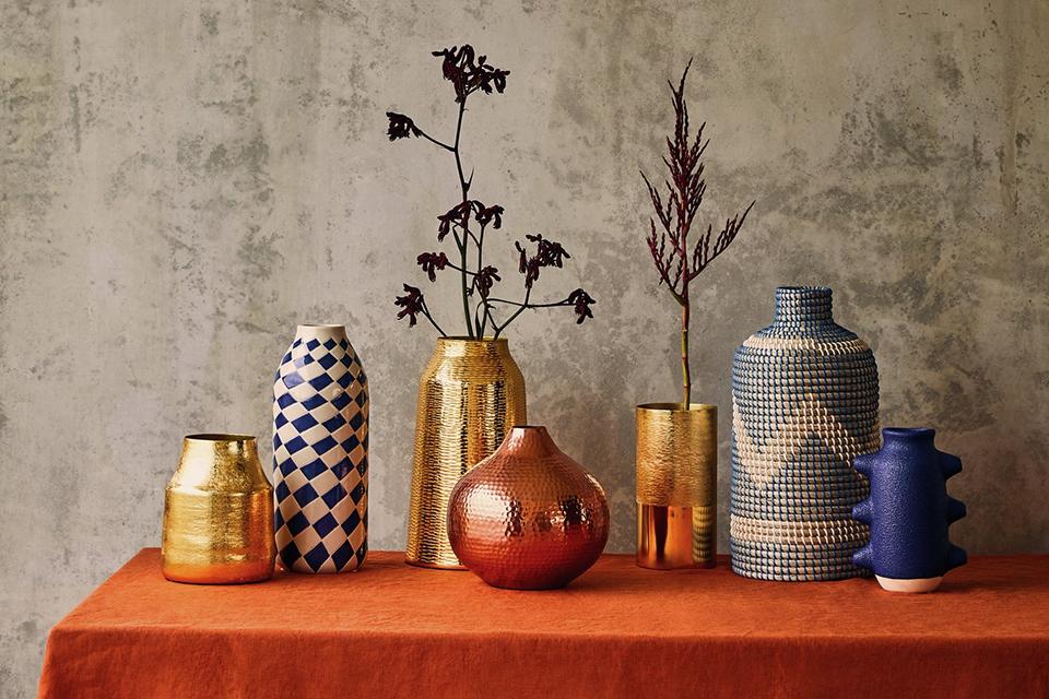 A selection of vases on an orange tablecloth.