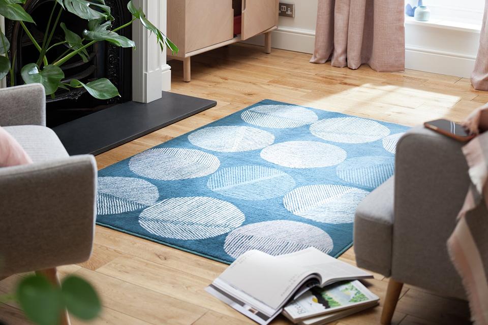 Blue patterned rug next to sofa in living room.