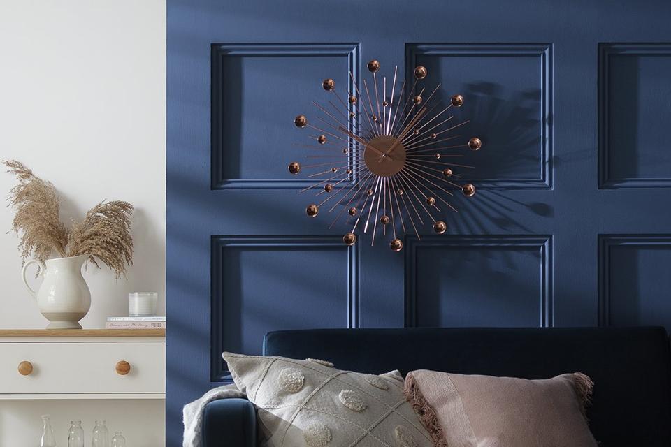 Image of a rose gold clock on a blue wall.