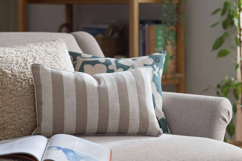 Stripecream long cushion on sofa next to cushions.